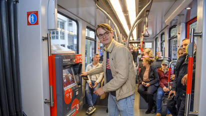 Jongen bij de kaartverkoopautomaat Jongen koopt kaartje bij HTM kaartverkoopautomaat in HTM tram