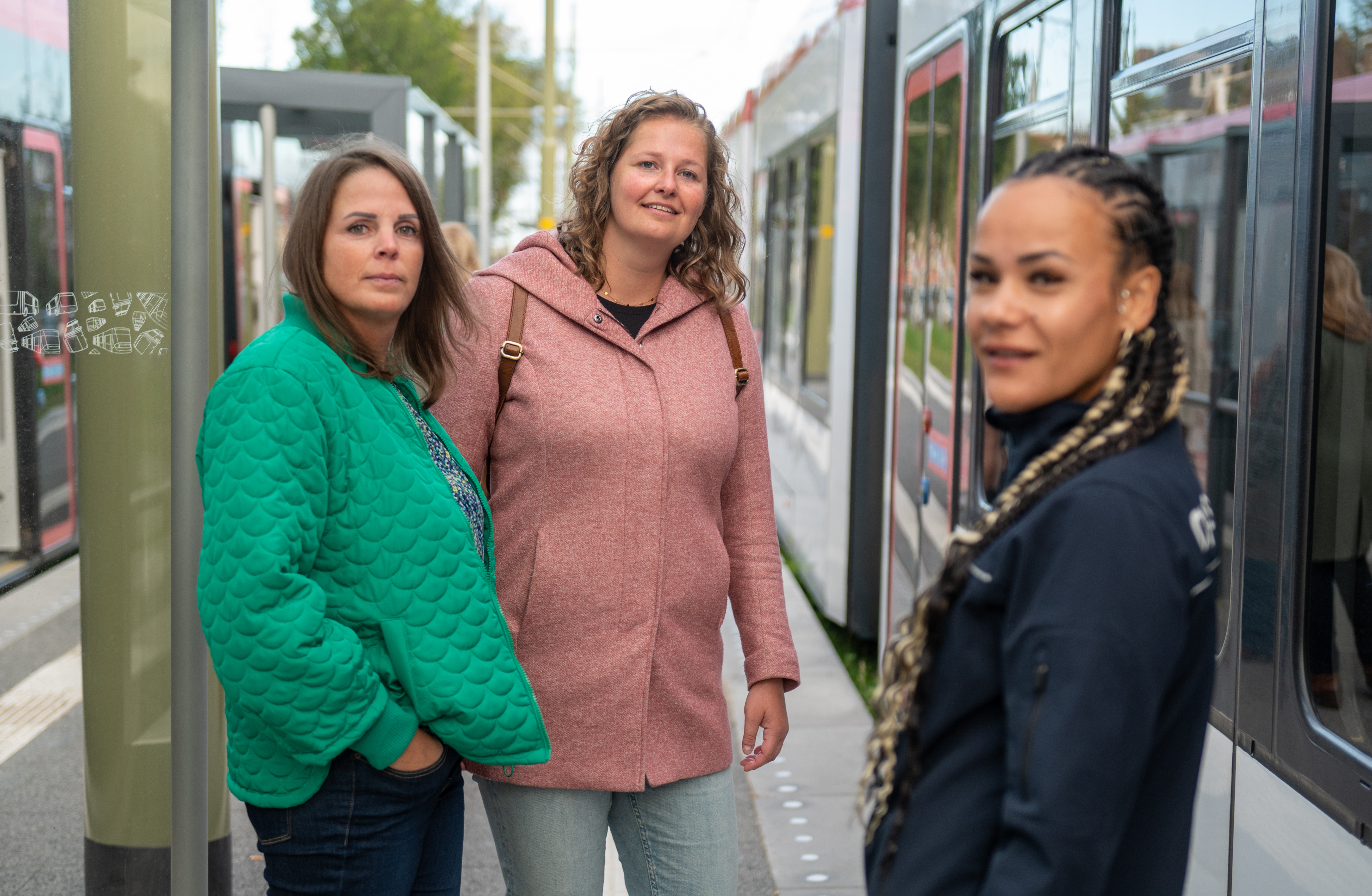 HTM controleur met 2 reizigers naast HTM tram