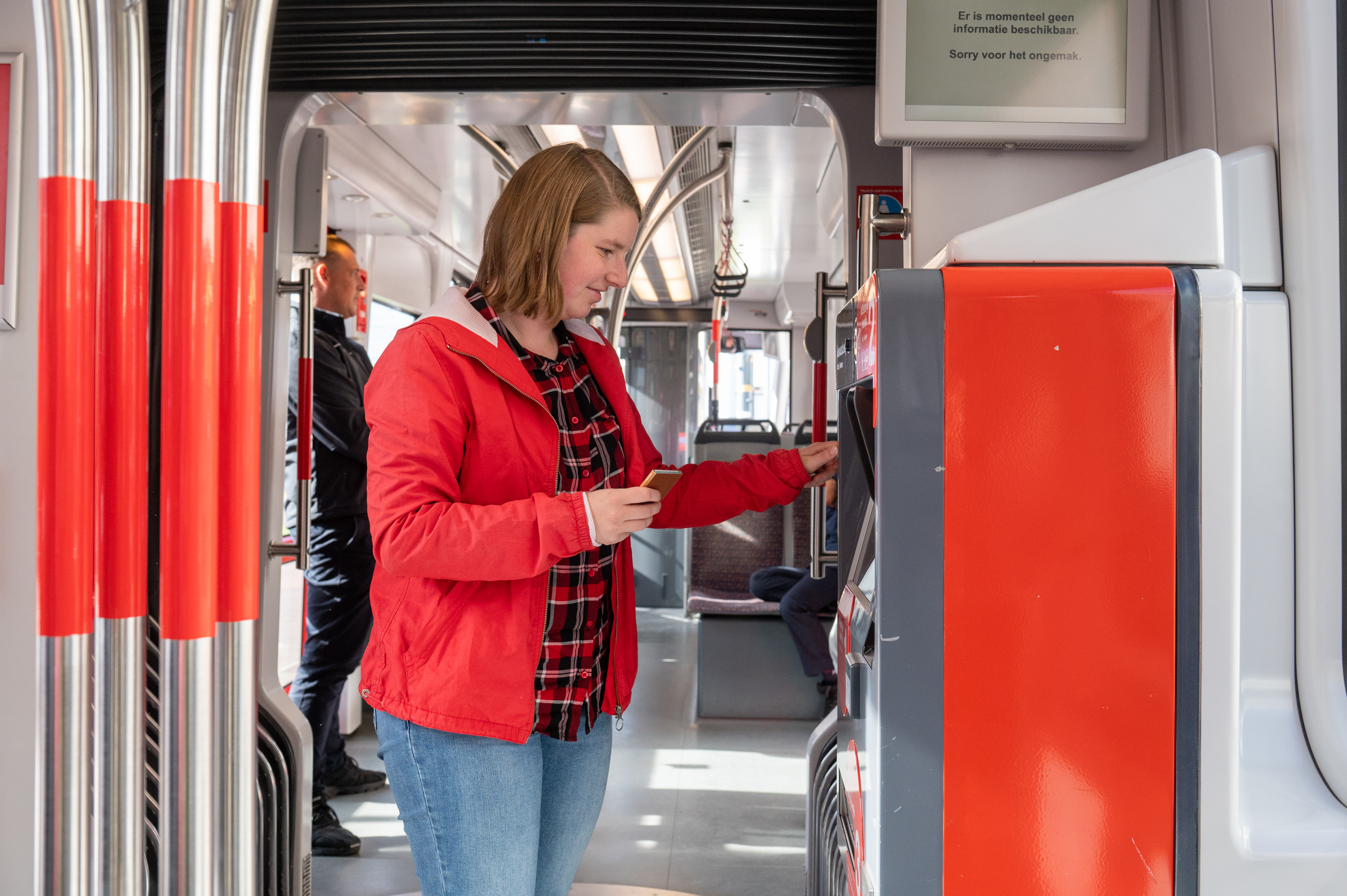 Vrouw koopt kaartje bij HTM kaartverkoopautomaat in HTM tram