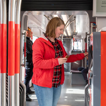 Vrouw koopt kaartje bij kaartverkoopautomaat Vrouw koopt kaartje bij HTM kaartverkoopautomaat in HTM tram