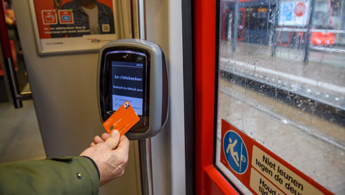 Reiziger checkt uit met pinpas HTM reiziger checkt uit met OVpay via zijn bankpas in een HTM tram