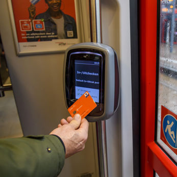 Reiziger checkt uit met pinpas HTM reiziger checkt uit met OVpay via zijn bankpas in een HTM tram