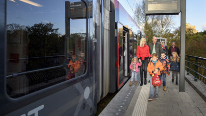 Reizigers met kinderen lopen naast HTM tram Reizigers met kinderen lopen naast HTM tram