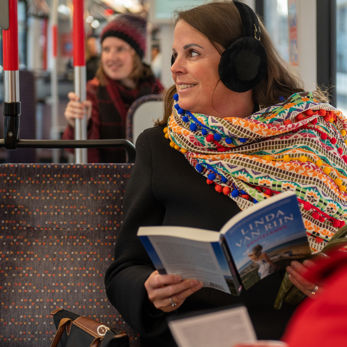 Vrouw leest boek in HTM tram en heeft oorwarmers op Vrouw leest boek in HTM tram en heeft oorwarmers op
