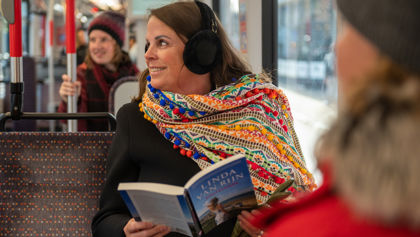 Vrouw leest boek in HTM tram en heeft oorwarmers op Vrouw leest boek in HTM tram en heeft oorwarmers op
