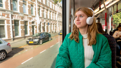 Vrouw zit in HTM tram en luister muziek met koptelefoon op Vrouw zit in HTM tram en luister muziek met koptelefoon op