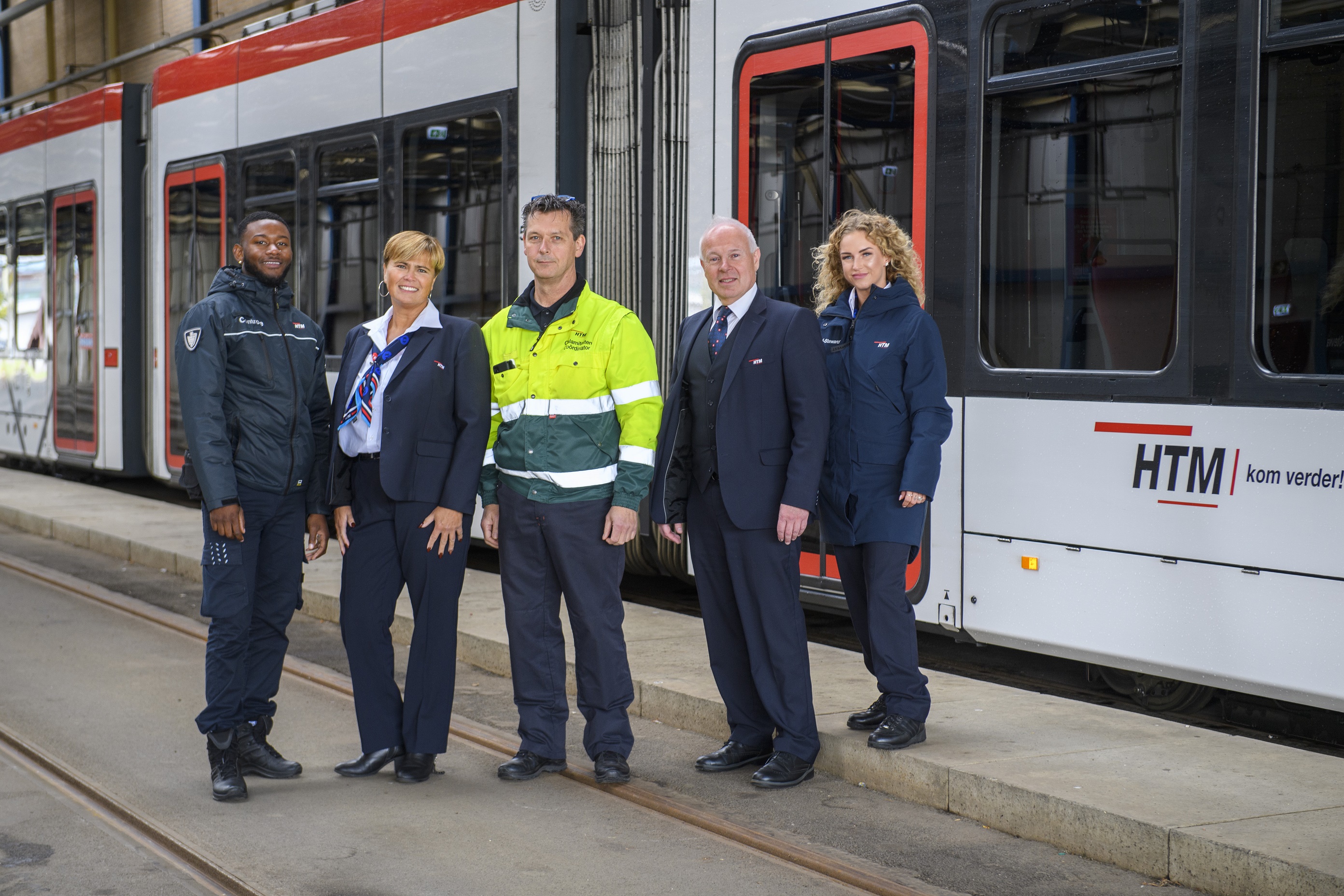 HTM medewerkers naast HTM tram kijken naar de camera