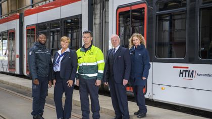 Medewerkers naast tram HTM medewerkers naast HTM tram kijken naar de camera