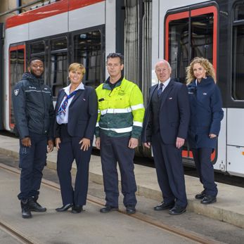 Medewerkers naast tram HTM medewerkers naast HTM tram kijken naar de camera
