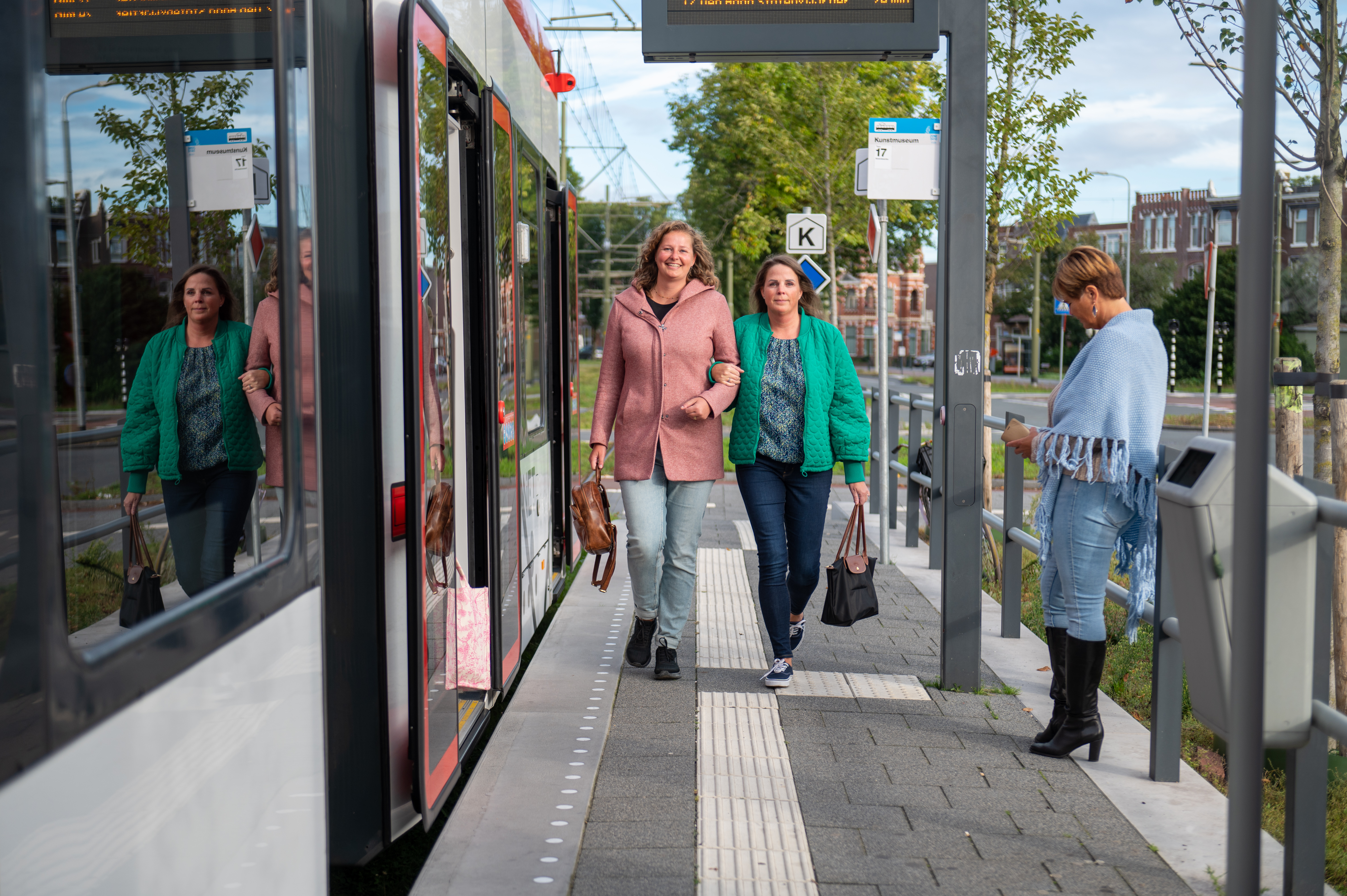 Reizigers op halte naast HTM tram kijken naar de camera