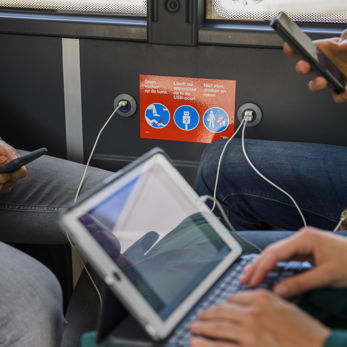 Reizigers laden telefoons en tablet op in HTM bus Reizigers laden telefoons en tablet op in HTM bus