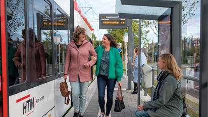 Reizigers lopen op tramhalte Reizigers lopen op halte naast HTM tram