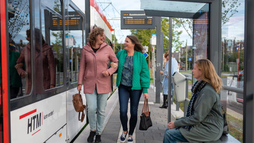 Reizigers lopen op tramhalte Reizigers lopen op halte naast HTM tram