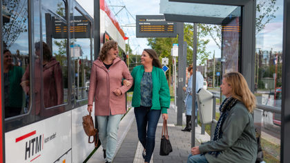 Reizigers lopen op tramhalte Reizigers lopen op halte naast HTM tram