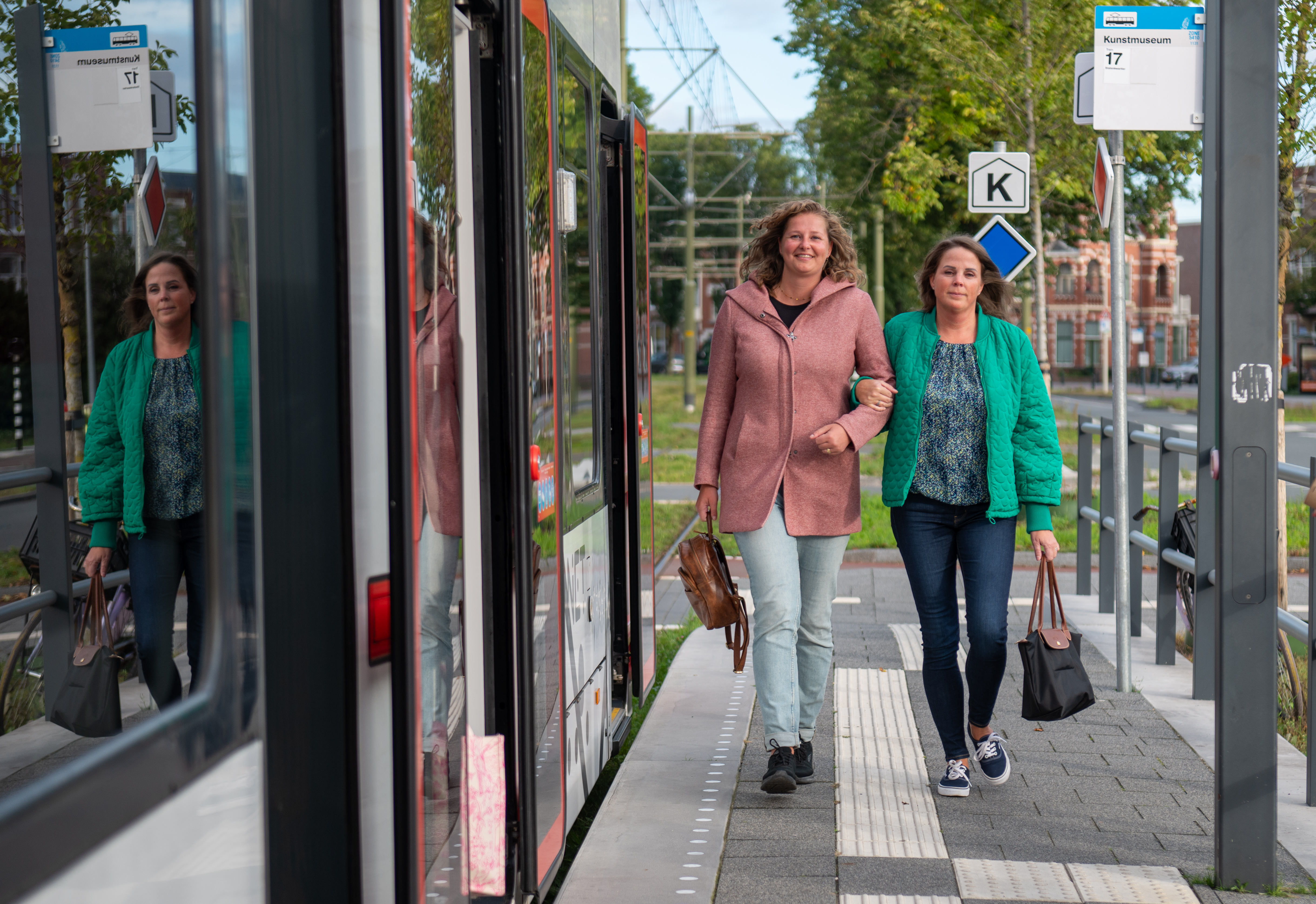 Reizigers lopen op halte naast HTM tram en kijken naar de camera