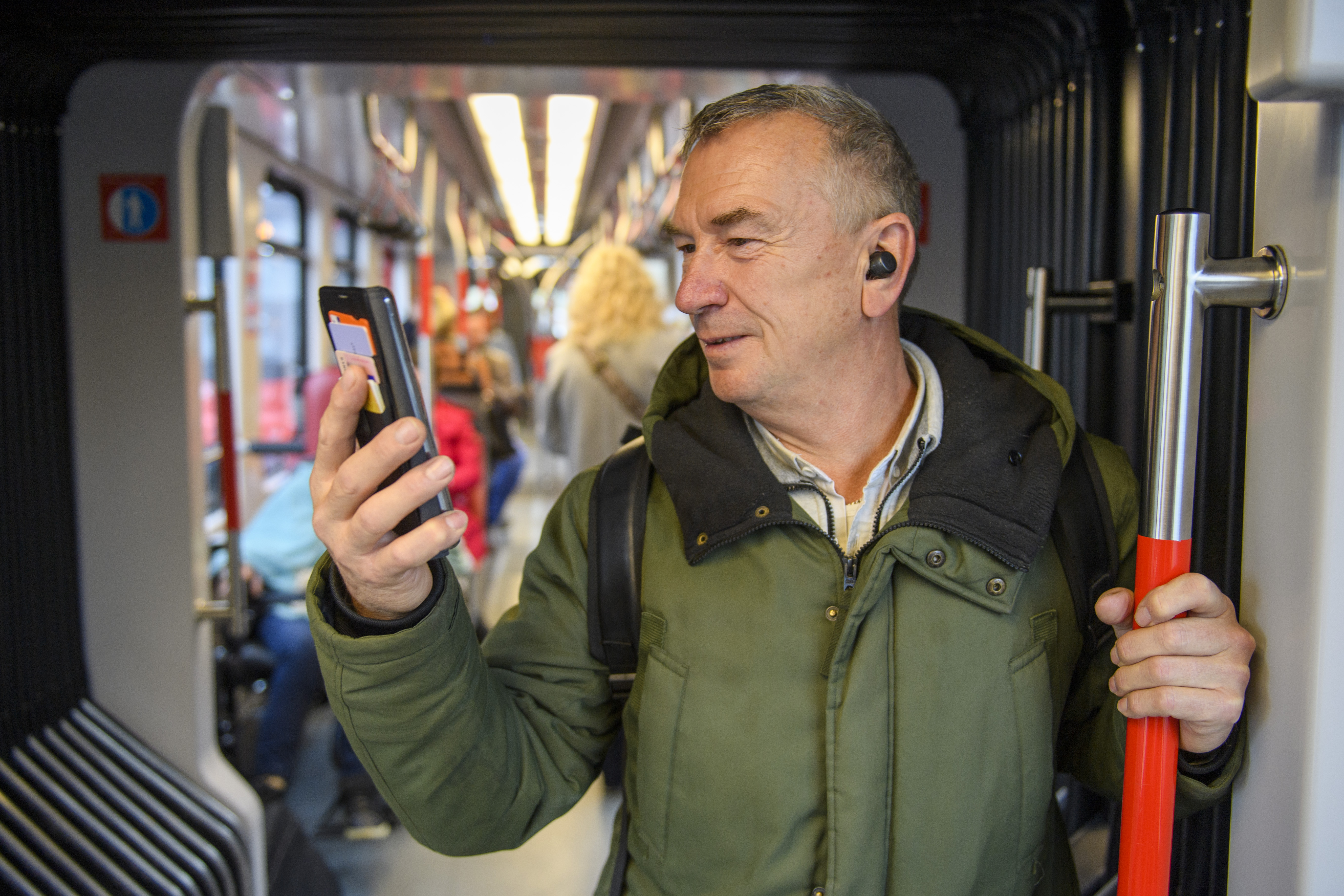 Man staat in HTM tram en kijkt op telefoon