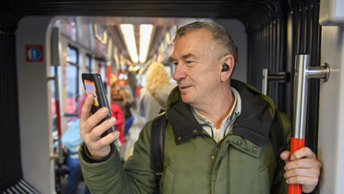Man staat in HTM tram en kijkt lachend op zijn telefoon Man staat in HTM tram en kijkt lachend op zijn telefoon