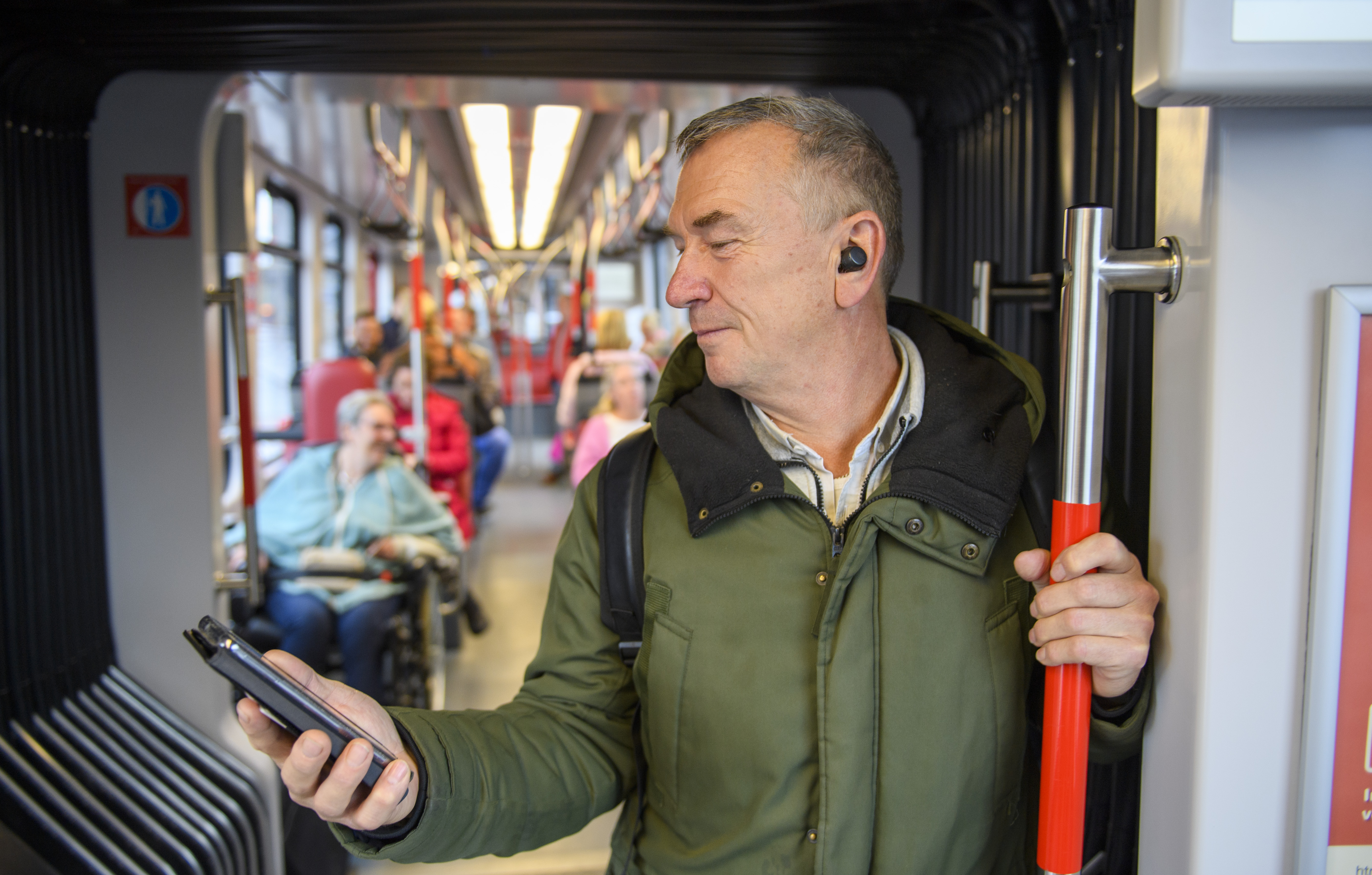 Man staat in HTM tram en kijkt op telefoon