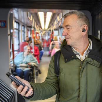Man staat in tram Man staat in HTM tram en kijkt op telefoon