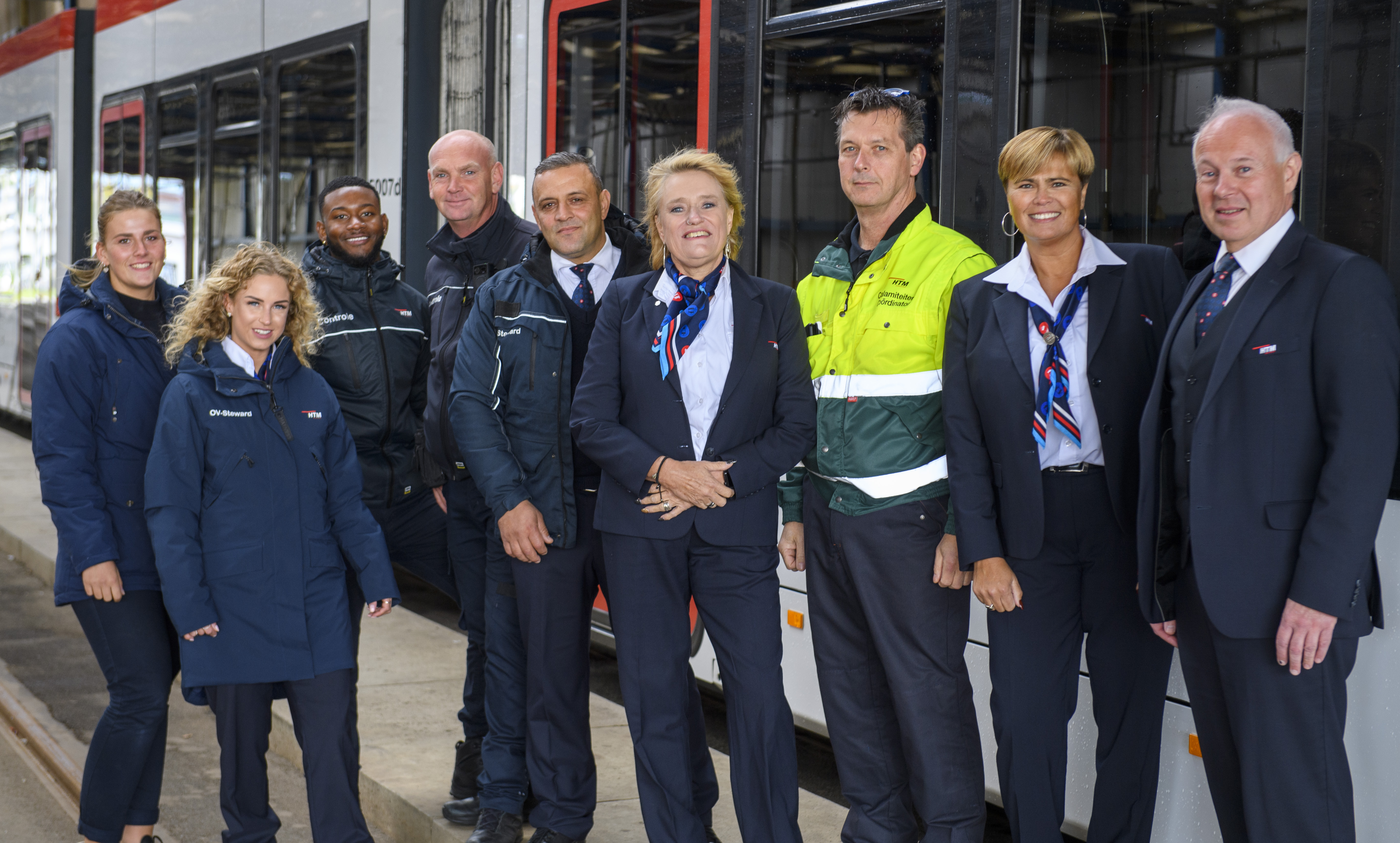 HTM medewerkers naast HTM tram kijken naar de camera