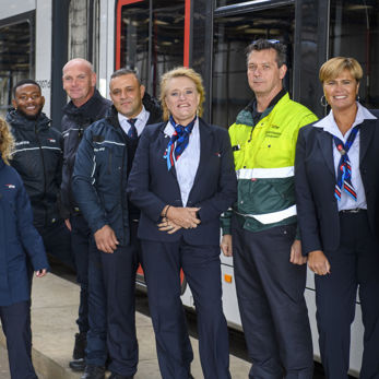 Medewerkers naast tram HTM medewerkers naast HTM tram kijken naar de camera