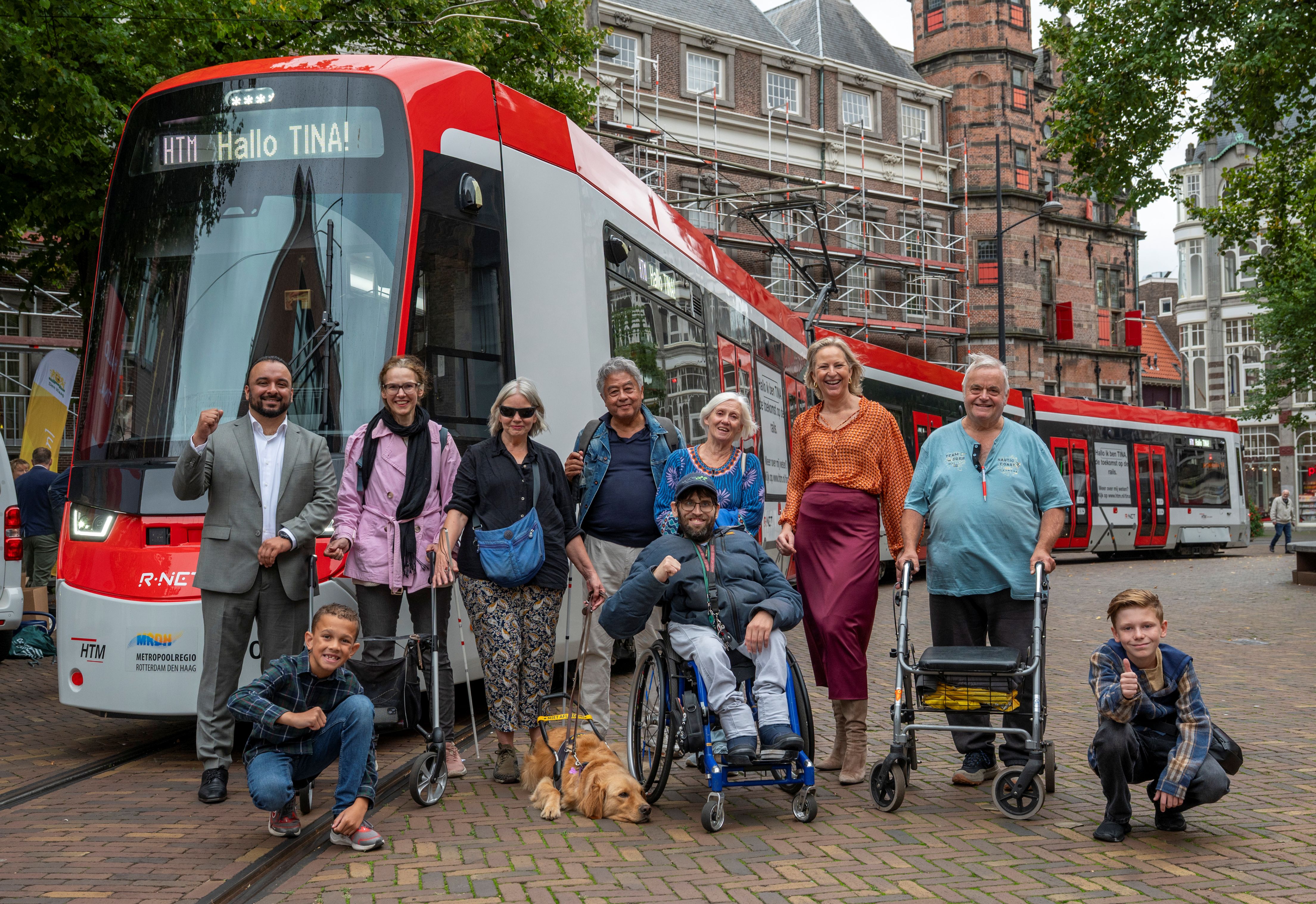Vertegenwoordigers van de stichting Voorall staan samen met Thea de Vries, algemeen directeur HTM en wethouder Mahmood voor de TINA-tram