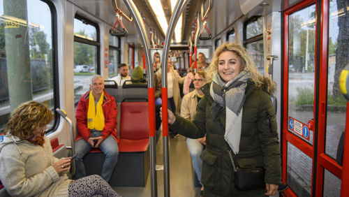 Reizigers in tram Reizigers staan en zitten in HTM tram en kijken naar de camera