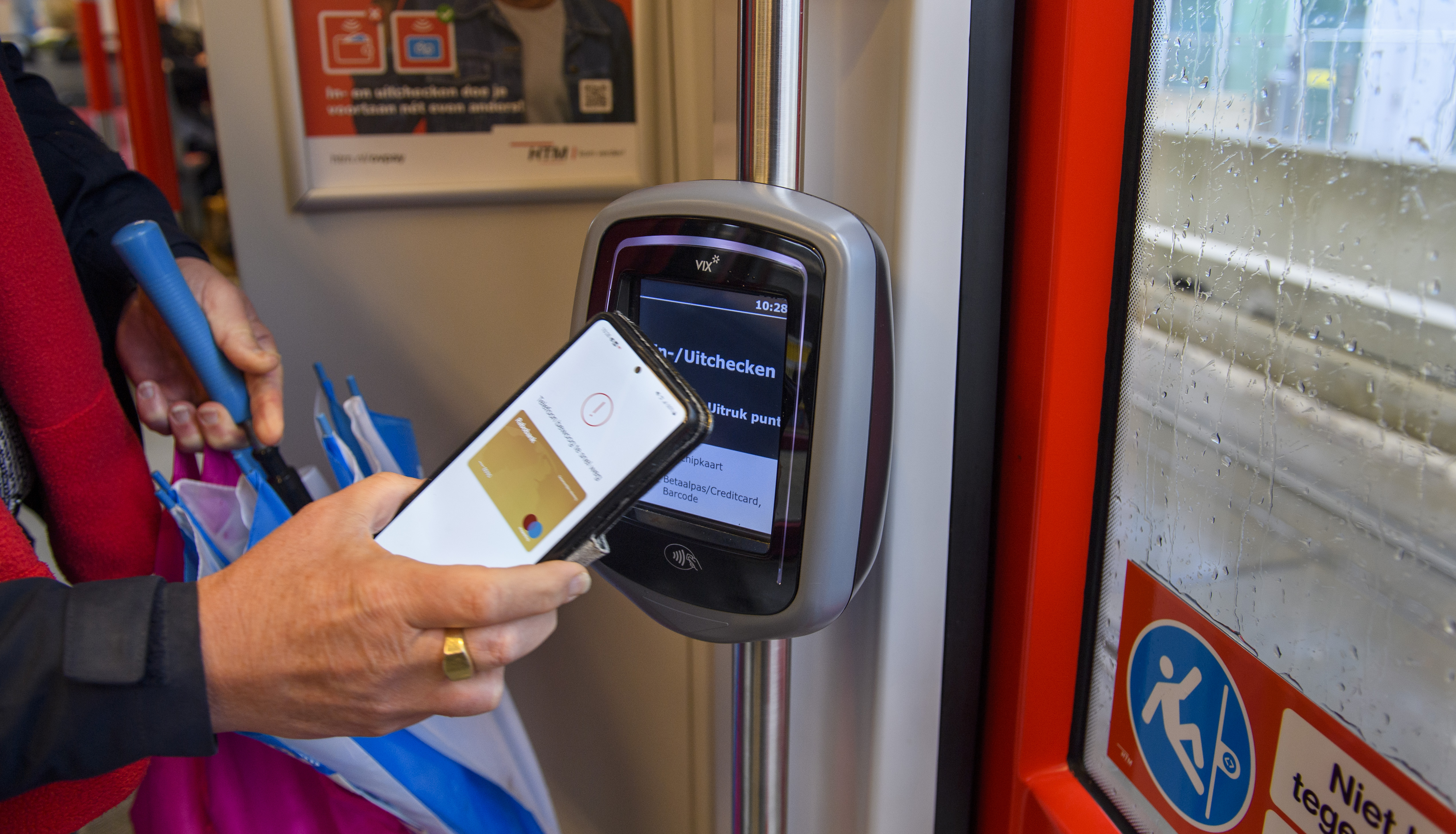 Reiziger checkt uit met OVpay via haar telefoon in een HTM tram