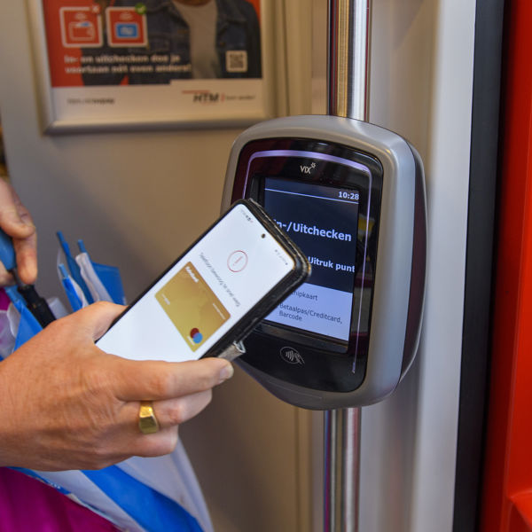 HTM reiziger checkt uit met telefoon Reiziger checkt uit met OVpay via haar telefoon in een HTM tram