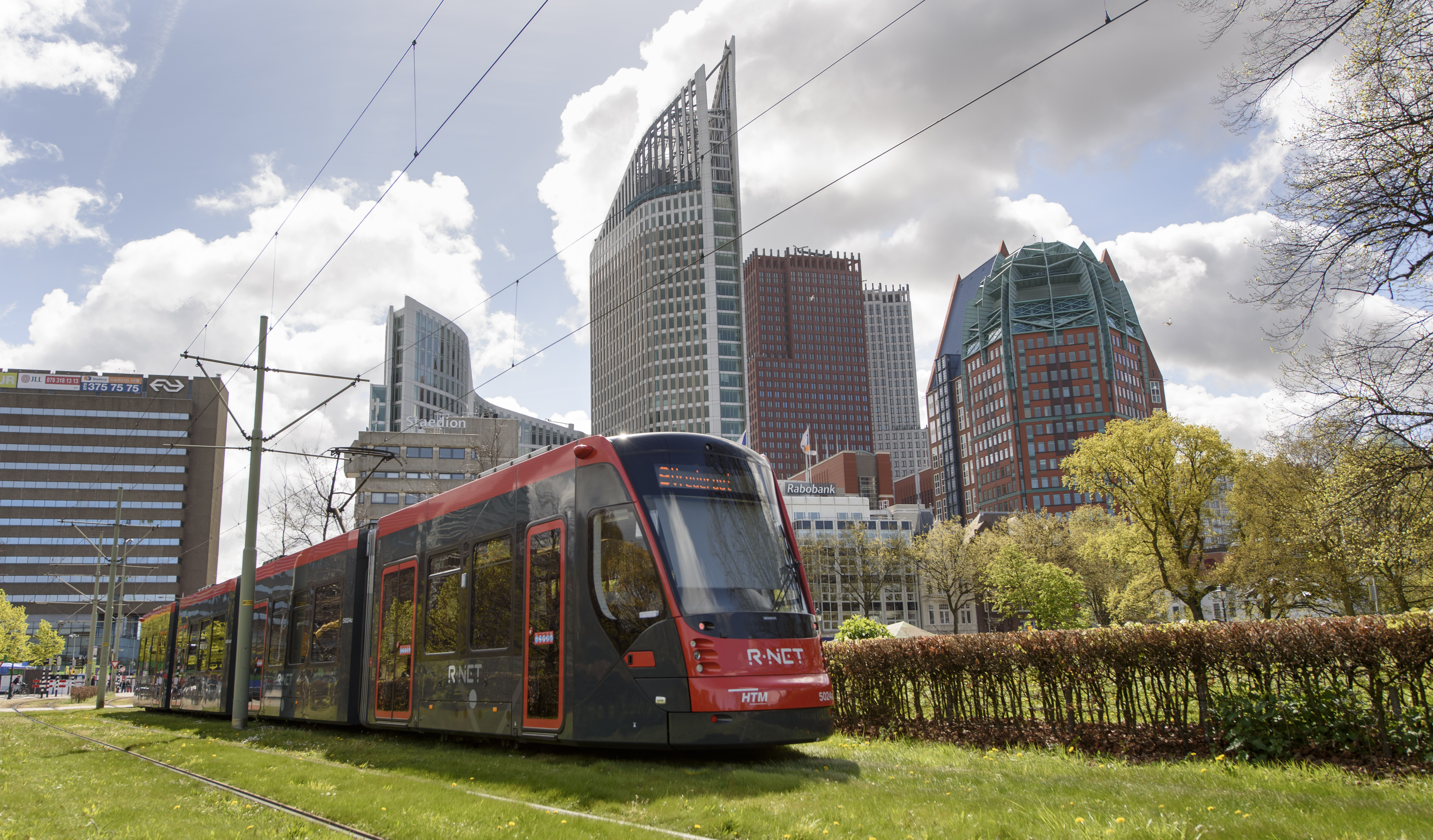 Aveniotram grijs-rood met de skyline van Den Haag op de achtergrond