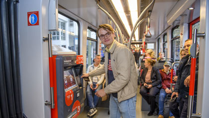 Jongen bij de kaartverkoopautomaat Jongen koopt kaartje bij HTM kaartverkoopautomaat in HTM tram