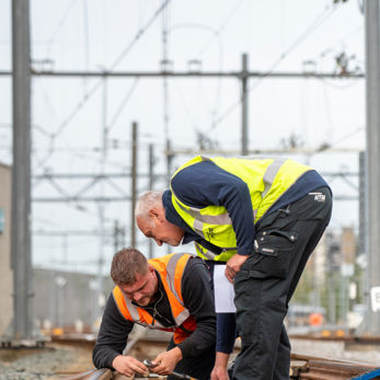 Twee monteurs repareren het spoor en draaien schroeven aan Twee monteurs repareren het spoor