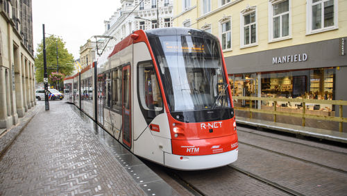 Wit met rode tram rijdt langs winkels Wit met rode HTM tram rijdt langs winkels in Den Haag