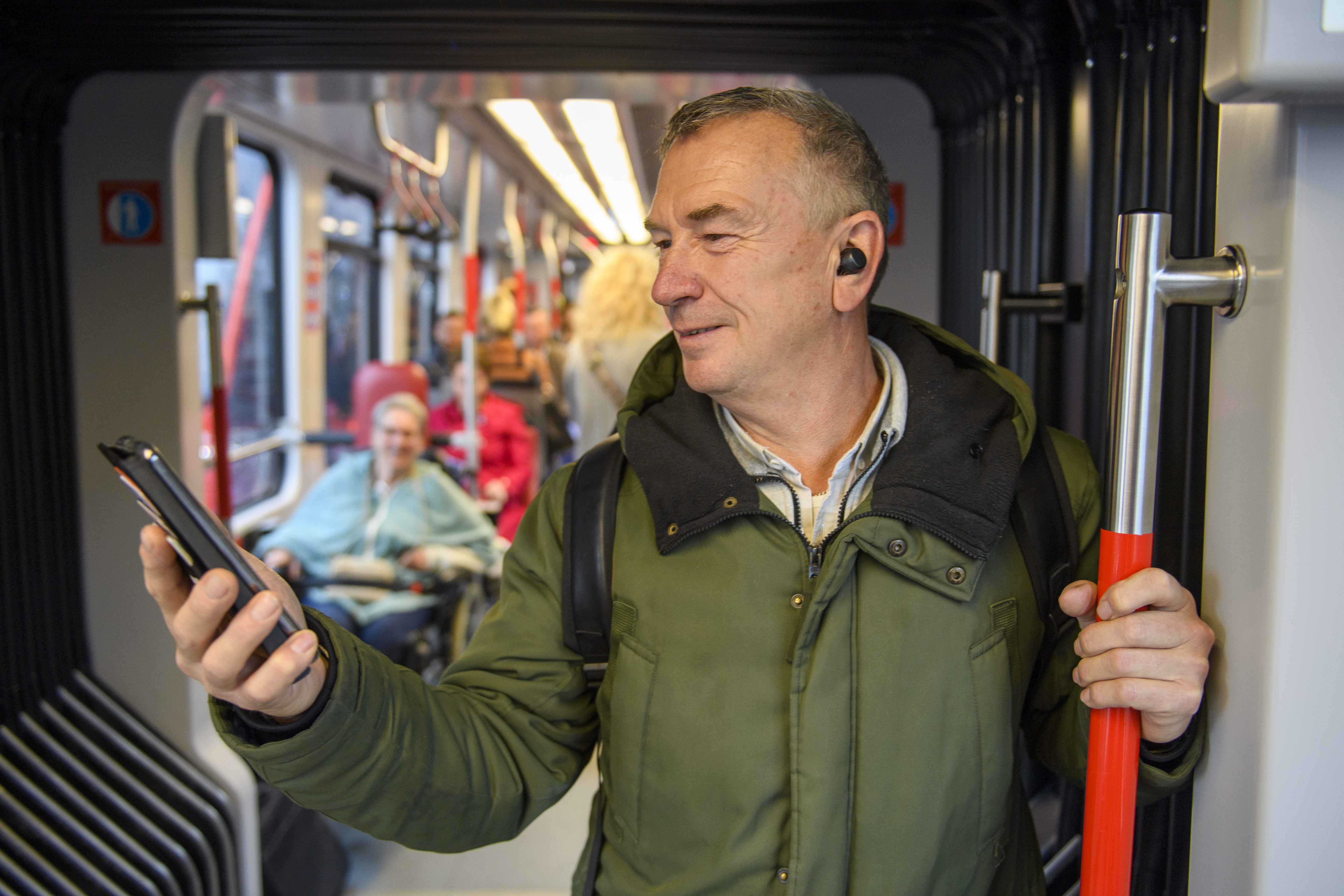 Man staat in HTM tram en kijkt op telefoon