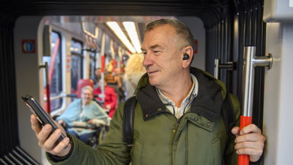 Man staat in tram Man staat in HTM tram en kijkt op telefoon