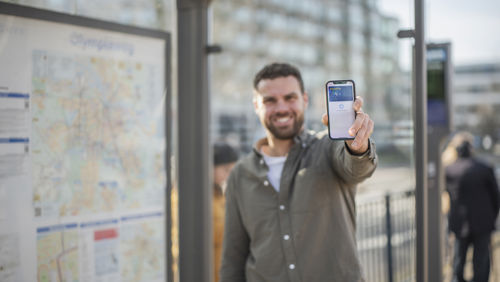 Man in bushokje die zijn mobile telefoon laat zien met daarop zijn betaalpas Man in bushokje die zijn mobile telefoon laat zien met daarop zijn betaalpas
