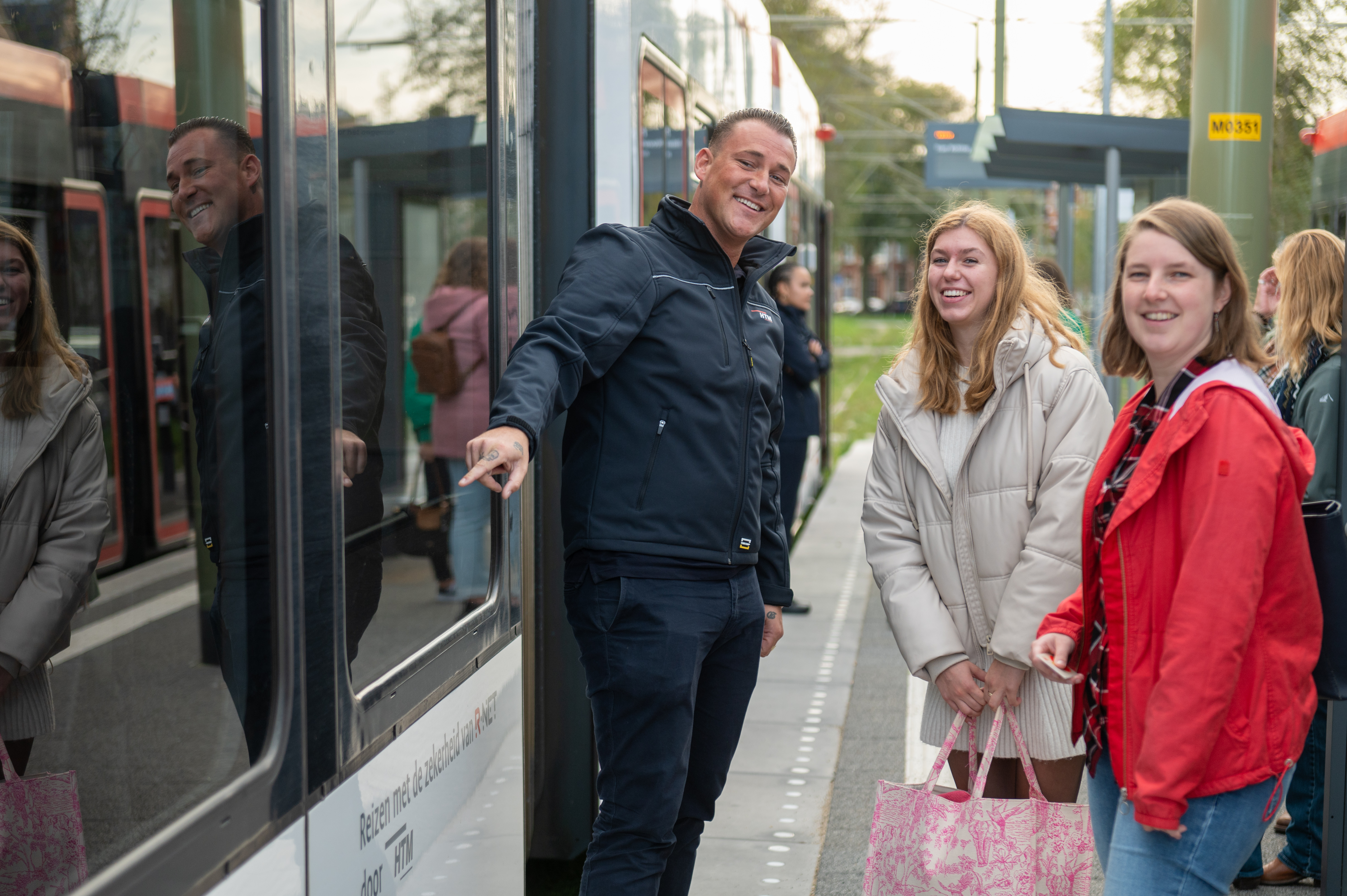 HTM OV steward met reizigers naast HTM tram