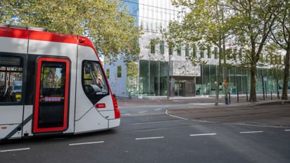 Zijaanzicht Aveniotram voor het gebouw van de Hoge Raad in Den Haag HTM Avenio rood-wit voor de Hoge Raad Den Haag
