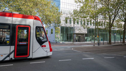 Zijaanzicht Aveniotram voor het gebouw van de Hoge Raad in Den Haag HTM Avenio rood-wit voor de Hoge Raad Den Haag