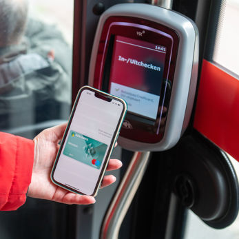 Reiziger checkt in met telefoon Reiziger checkt in met OV-pay in HTM tram