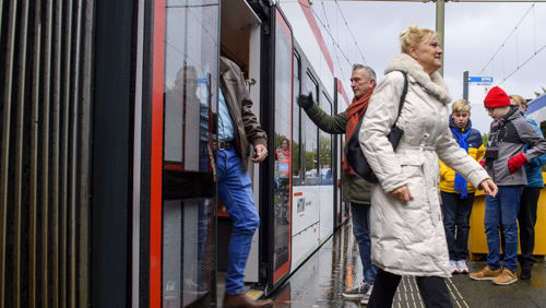 Reizigers stappen in en uit bij halte Reizigers stappen in en uit HTM tram bij tramhalte