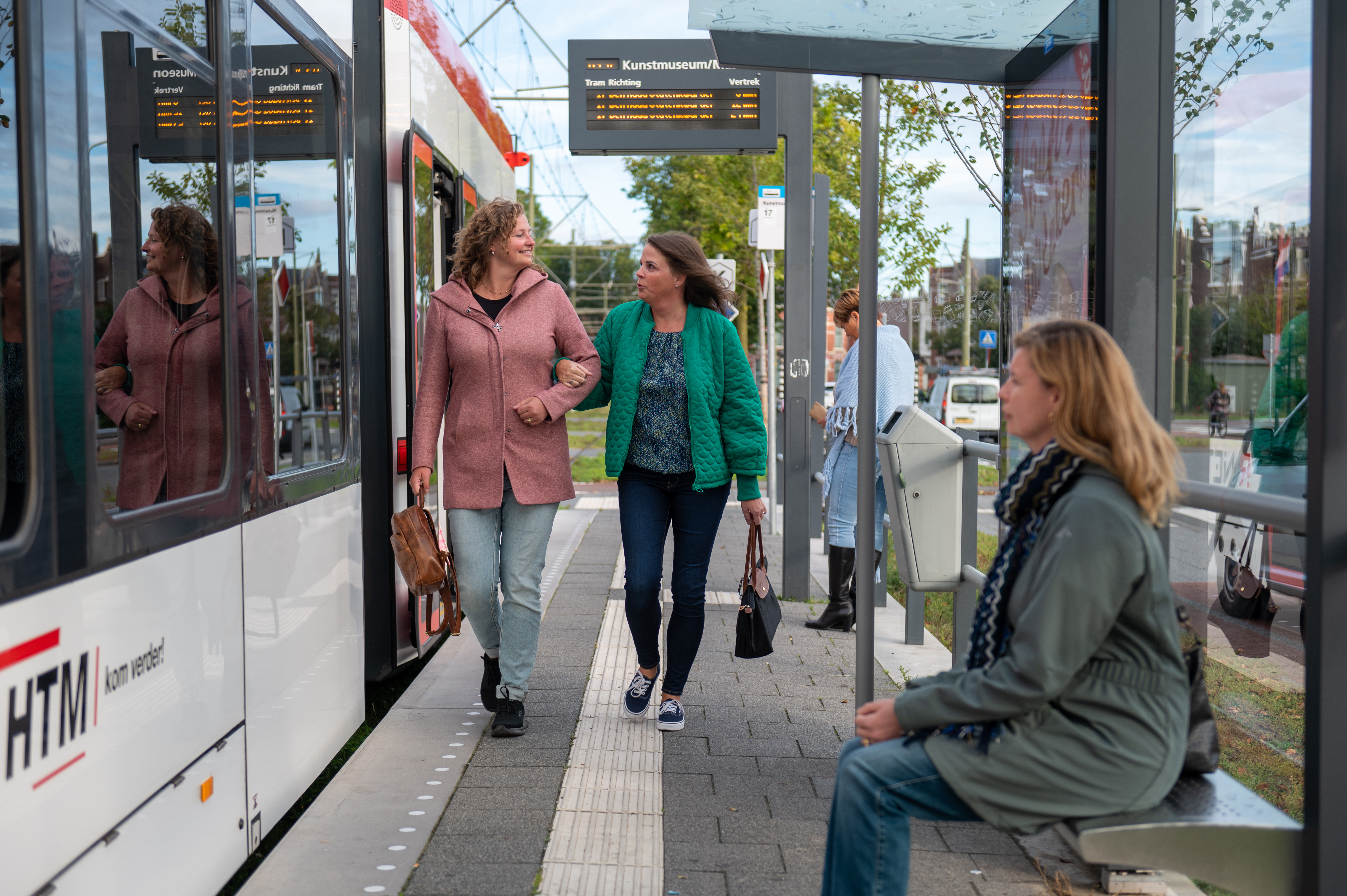 HTM reizigers lopen op tramhalte naast HTM tram