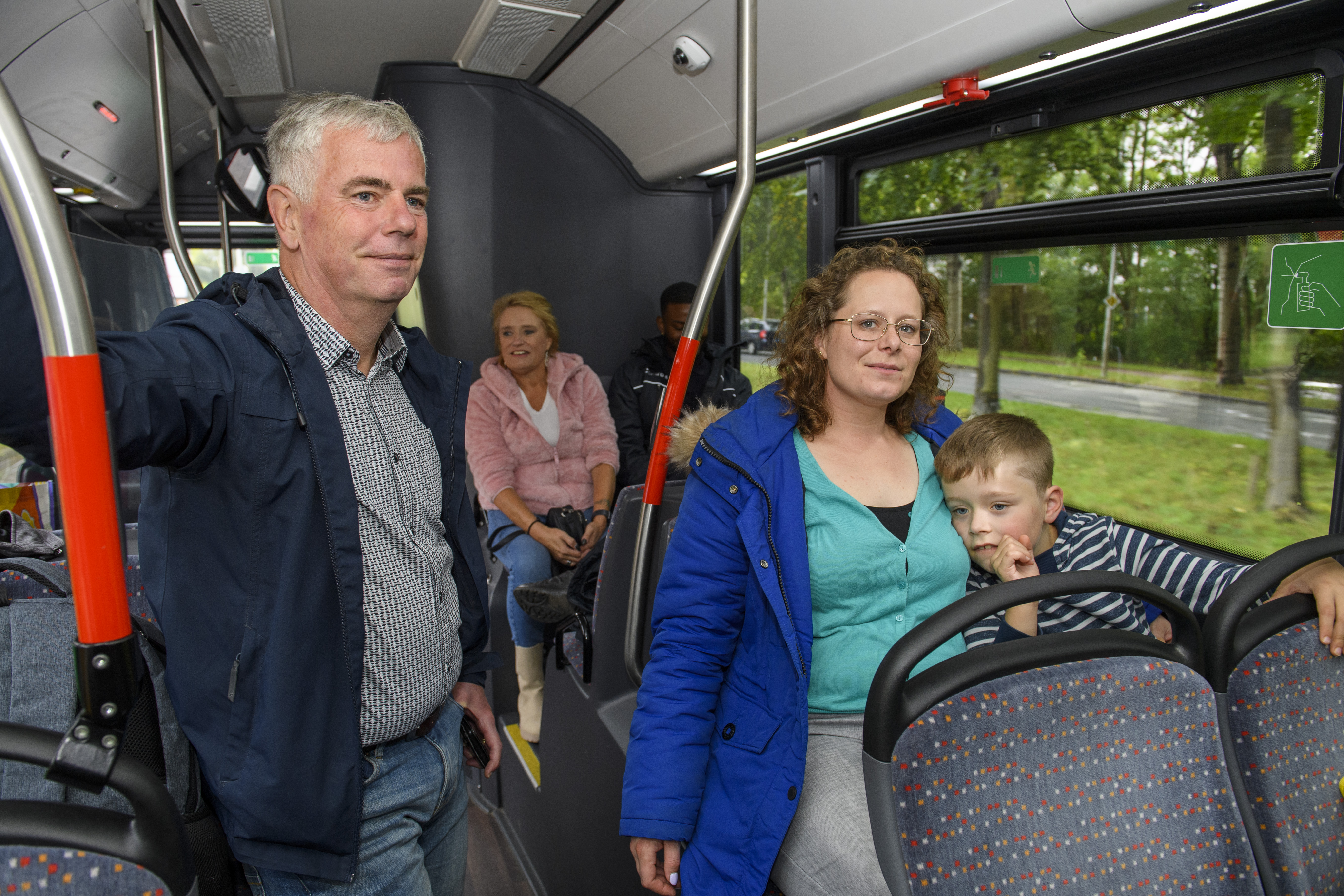 Reizigers zitten en staan in HTM bus en kijken naar voren