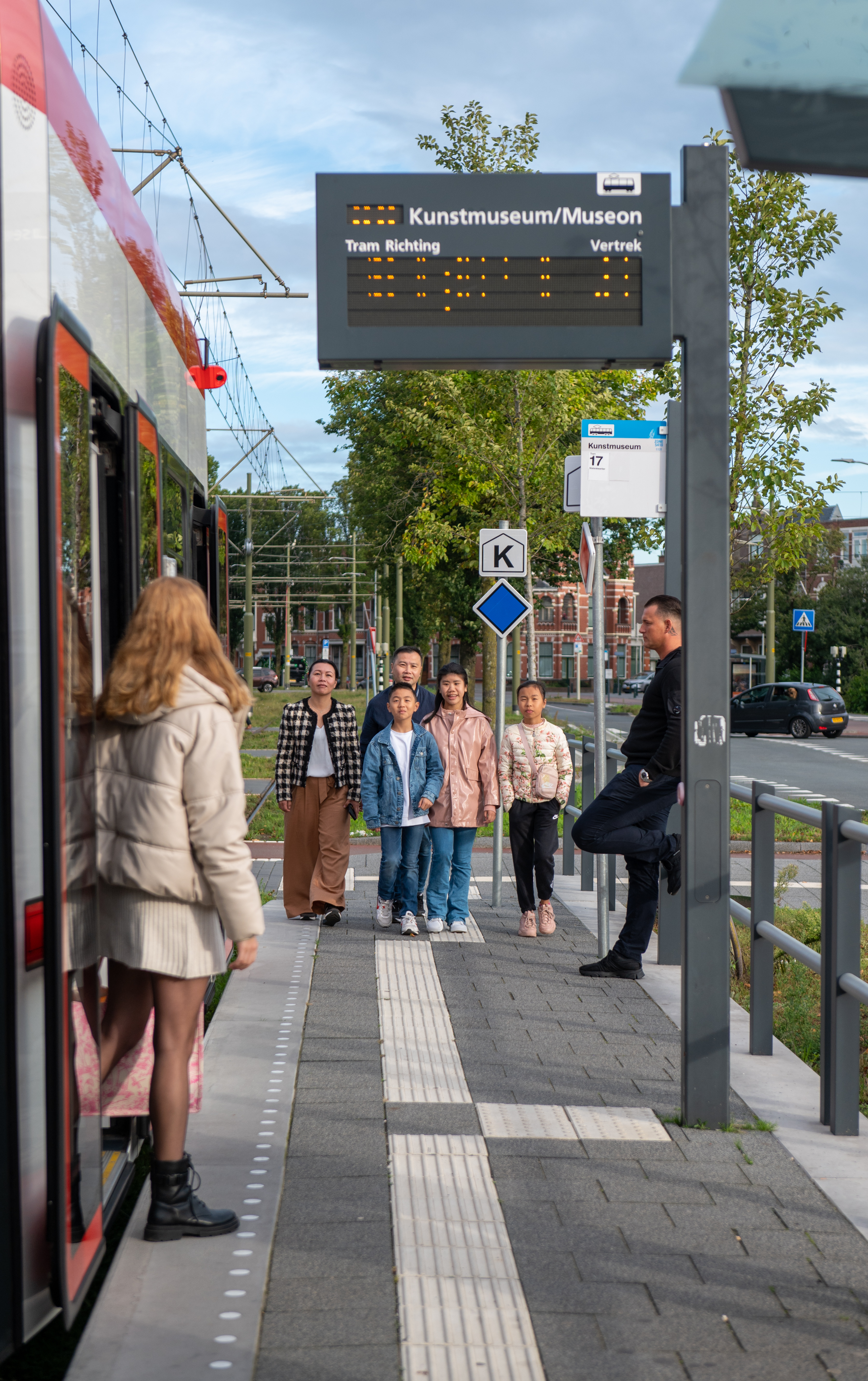 Gezin staat naast HTM tram en lacht naar de camera