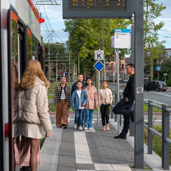 Gezin naast HTM tram Gezin staat naast HTM tram en lacht naar de camera