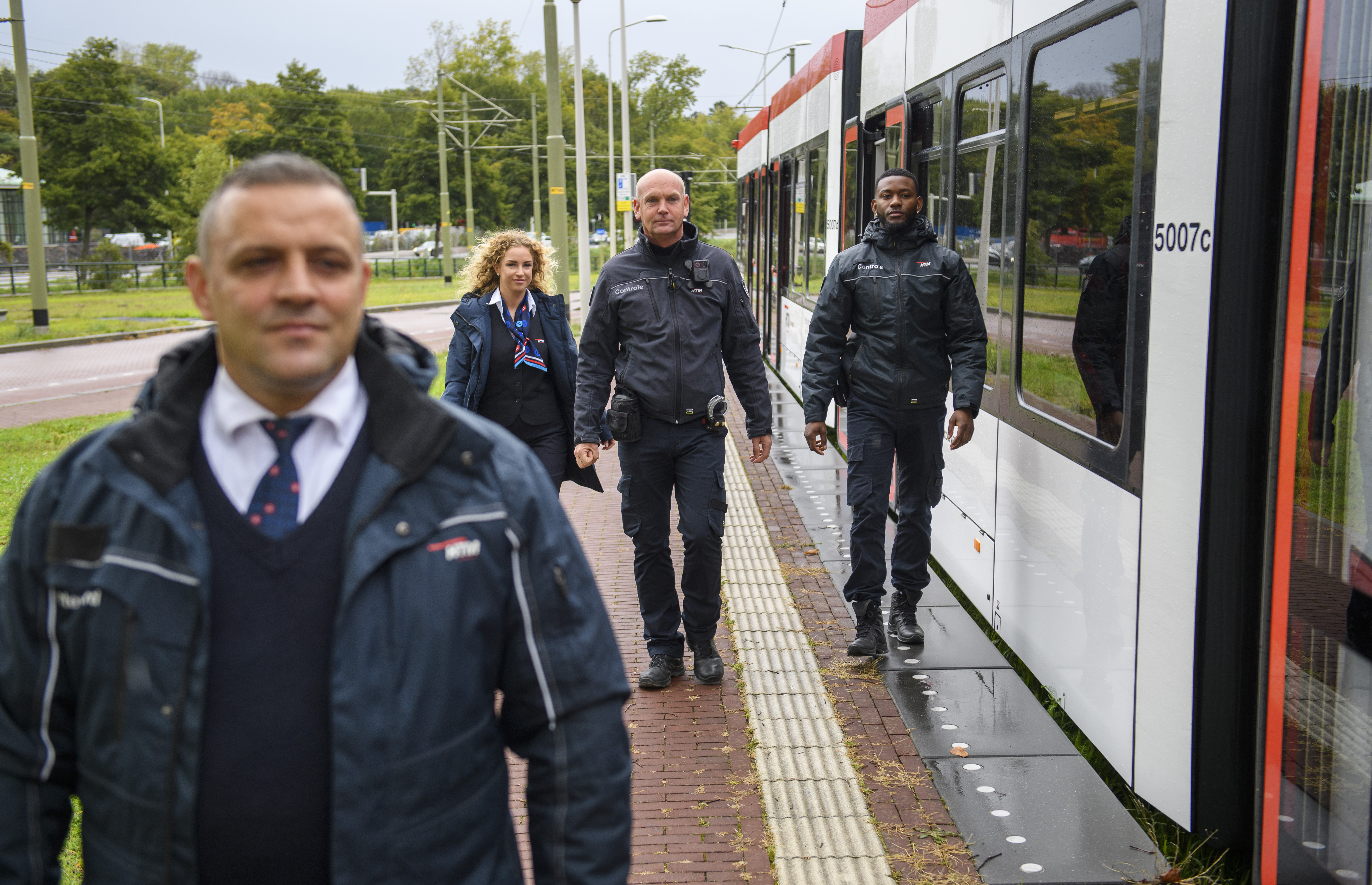 HTM BOA's lopen naast HTM tram met zijn vieren