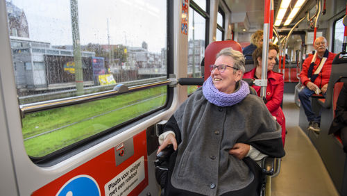 Reiziger in een rolstoel zit in HTM tram en kijkt naar buiten Reiziger in een rolstoel zit in HTM tram en kijkt naar buiten