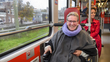 Reiziger in een rolstoel zit in tram en lacht naar de camera Reiziger in een rolstoel zit in HTM tram en lacht naar de camera