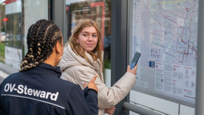 OV steward met reiziger naast kaart HTM steward met reiziger naast reisinformatie kaart