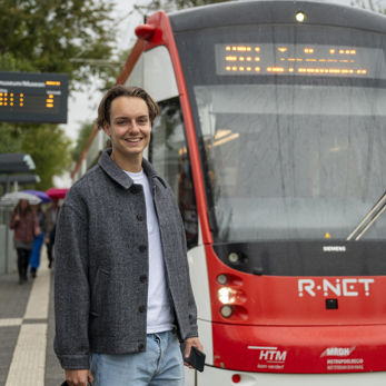 Jonge man op halte voor Avenio tram Jonge man op halte voor Avenio tram